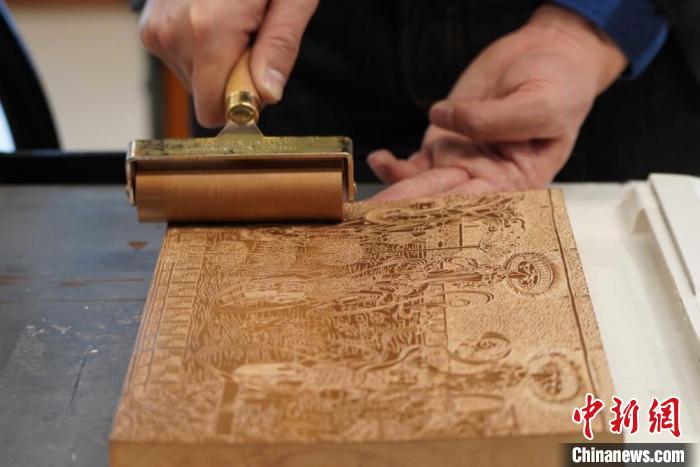 圖為徐晉林工作室工作人員正在給雕好壁畫的版面滾油墨。　九美旦增 　攝