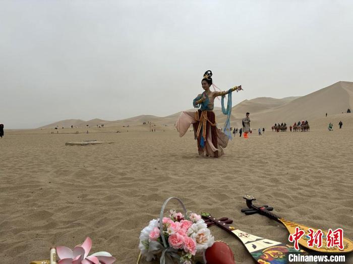 圖為2023年4月底，敦煌大漠“逐舞者”奧楠在鳴沙山月牙泉景區(qū)視頻直播敦煌舞?！●T志軍 攝