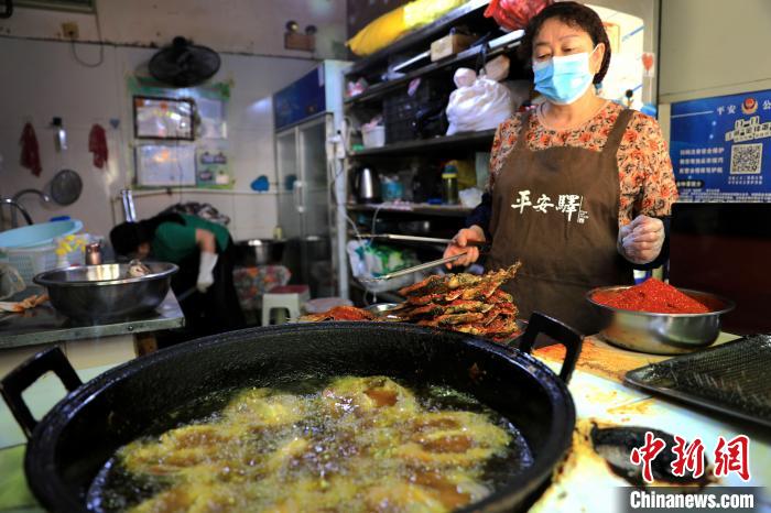 圖為平安驛·河湟民俗文化體驗地內(nèi)的商戶炸干板魚?！⊙Φ?攝